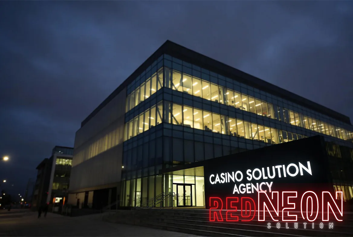 야경의 에이전시 사옥 — CASINO SOLUTION AGENCY 간판과 유리 파사드